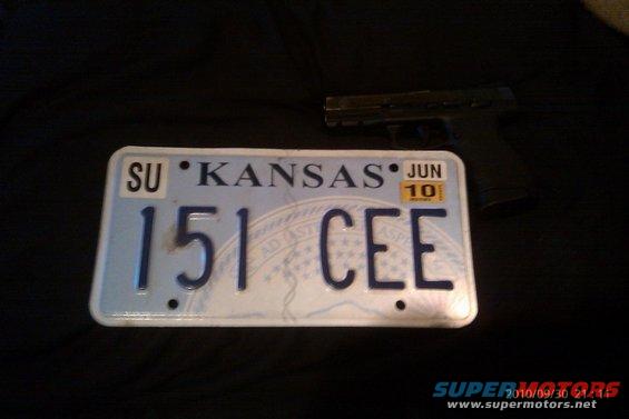 Kansas license plate that reads 151 CEE, with a handgun in the background