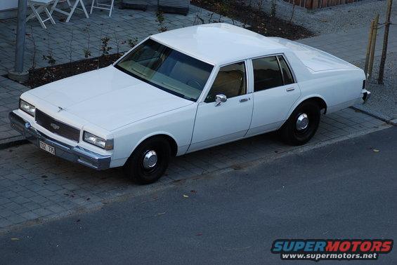 White sedan, 3q front view. License plate reads 102 775