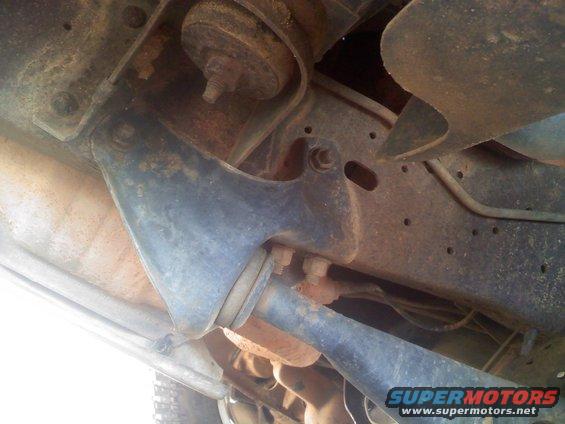 Underside view of rusty vehicle suspension with visible bolts and metal brackets