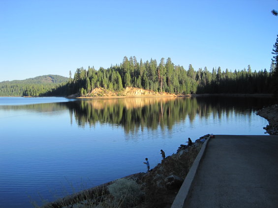 Lake with trees on the far bank and a few people fishing on the near bank