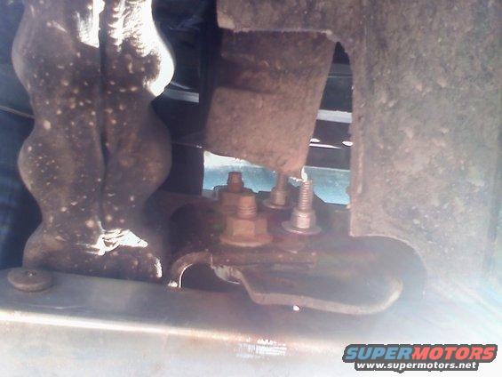 Undercarriage of a vehicle showing rusty mounting brackets and bolts