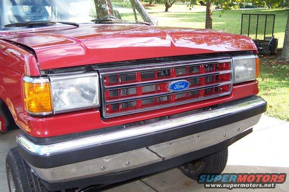 Red Ford truck front end with chrome bumper and red grille with blue Ford logo