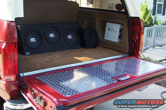 1990 Ford Bronco interior showing a triple subwoofer box and an amplifier mounted on the side panel