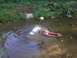 1994 Ford Escort - A toy SUV is partially submerged in muddy water, with a toy boat nearby.