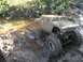 1994 Ford Escort - A vehicle is partially submerged in mud, with only parts of its wheels and body visible.