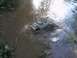 1994 Ford Escort - A remote control truck is stuck in the mud and water, with grass on the banks.