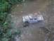 1994 Ford Escort - A toy truck is stuck in the mud, surrounded by water and vegetation.