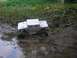 1994 Ford Escort - RC monster truck navigating a muddy trail.