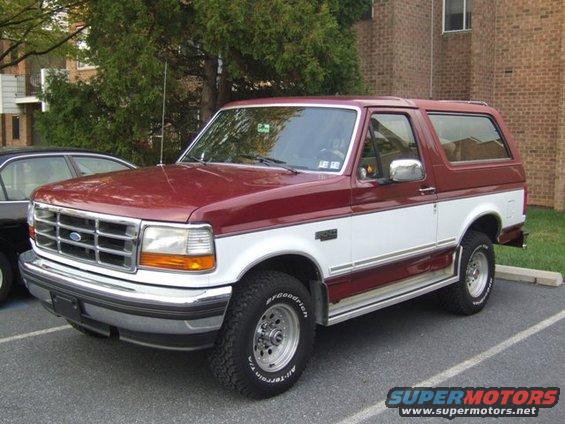 Maroon and white Ford Bronco parked in a lot, front 3/4 view