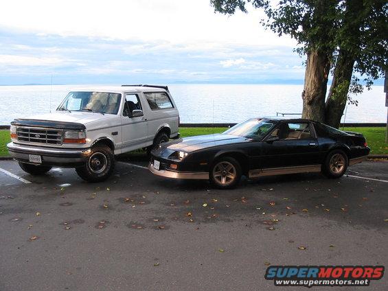 White 1992 Ford Bronco parked next to a black Chevrolet Camaro