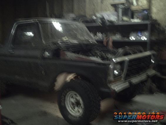 Dark 1978 Ford Bronco with hood open, showing engine, in a garage