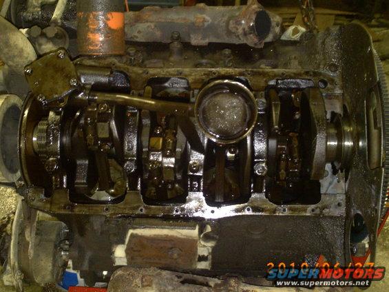 Engine block with crankshaft and connecting rods visible, oily