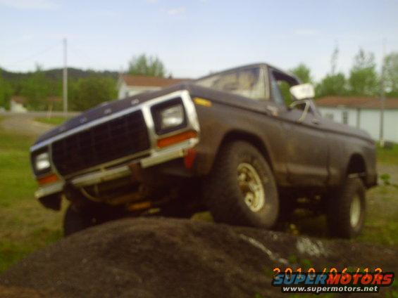 Brown 1978 Ford F-150 pickup truck on dirt mound, front 3/4 view