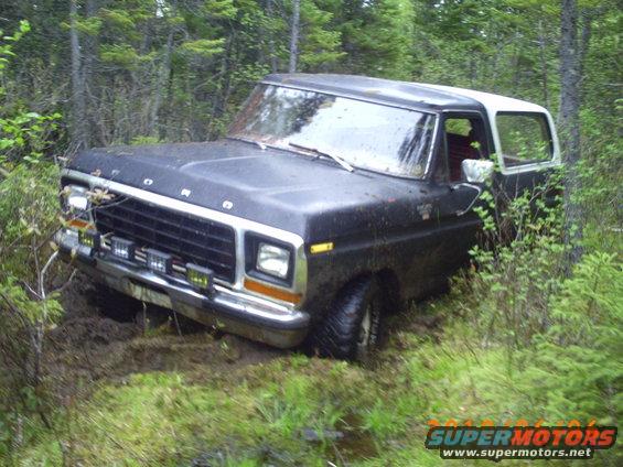 Black 1978 Ford Bronco stuck in muddy terrain with trees around
