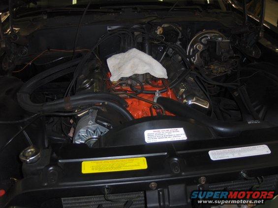 Engine bay with orange V8 engine and white rag on top
