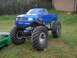 1994 Ford Escort - Blue RC monster truck with large tires, parked next to a green RC car.