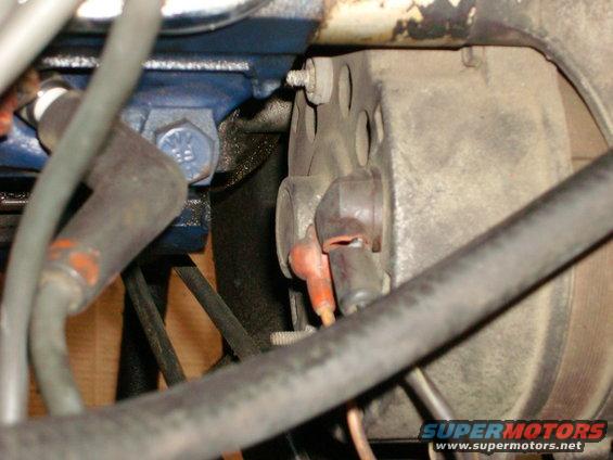 Close-up of engine components with wires and hoses, showing a distributor cap and spark plug wires