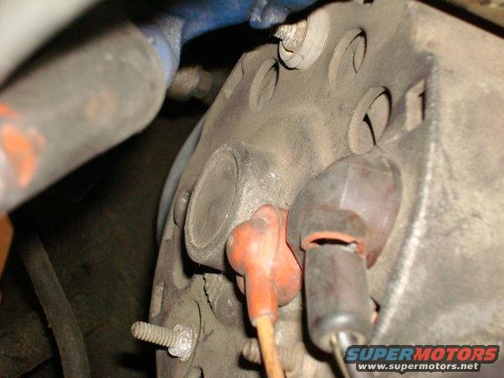 Close-up of engine part with orange and black spark plug wires attached