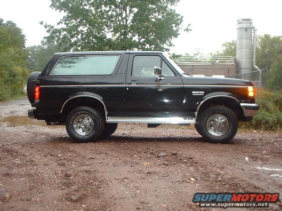 Black Ford Bronco SUV, side view, with chrome trim and a spare tire mounted on the rear door