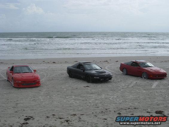 Three 1994 Ford Probes parked on a sandy beach near the ocean