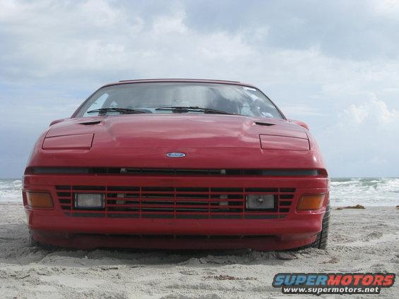 Red car with pop-up headlights on a sandy beach