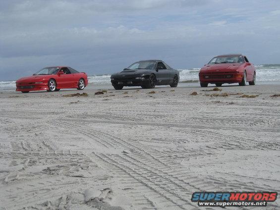 Three 1994 Ford Probes on a beach, one red, one black, one red