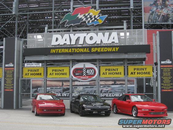 Three sports cars parked at Daytona International Speedway entrance