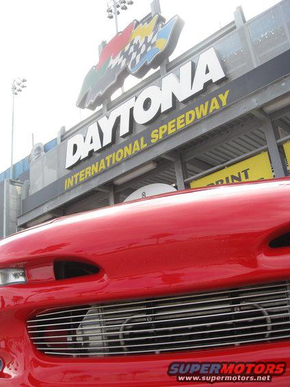 Red car front grille with Daytona International Speedway sign in background
