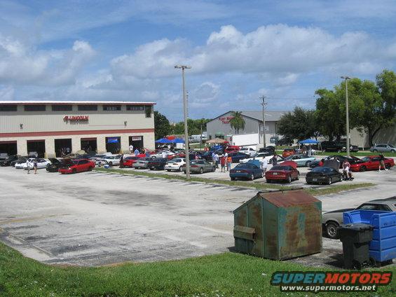 Parking lot with many cars, some with hoods up, in front of a building with 'LINCOLN' visible