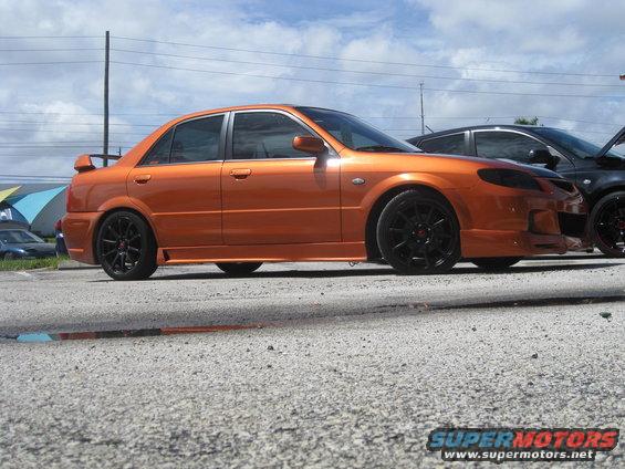 Orange sedan with black wheels and a spoiler parked next to a black car