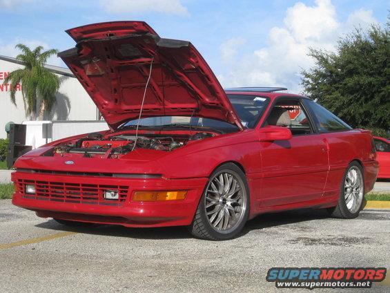 Red 1994 Ford Probe with hood open, aftermarket wheels