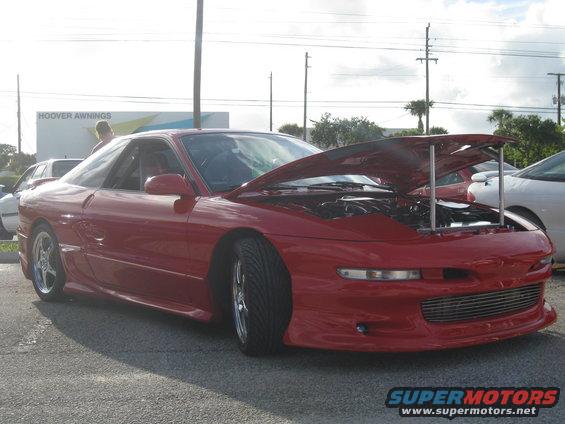 Red 1994 Ford Probe with hood open, parked next to another car