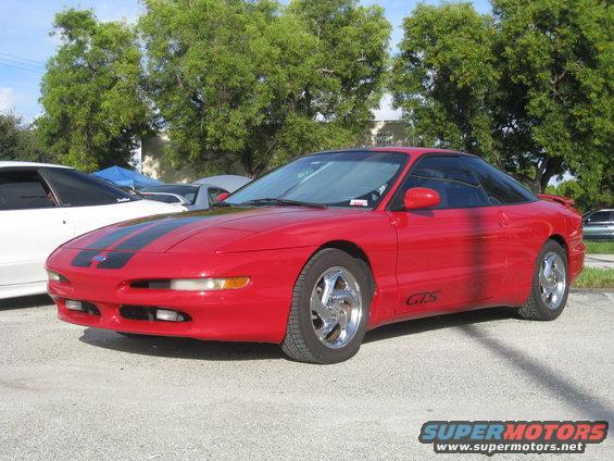 Red 1994 Ford Probe with black racing stripes on hood and roof. GTS badge on side