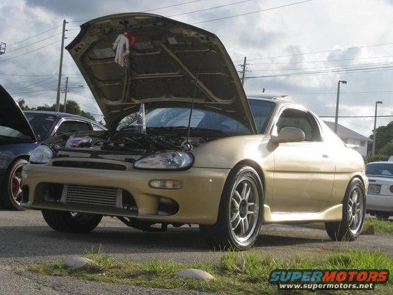 Gold 1994 Ford Probe with hood open, showing engine and aftermarket wheels