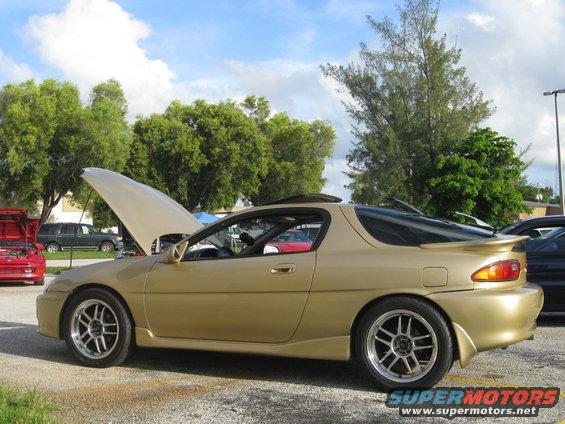 Gold coupe, hood open, side view. This is not a 1994 Ford Probe