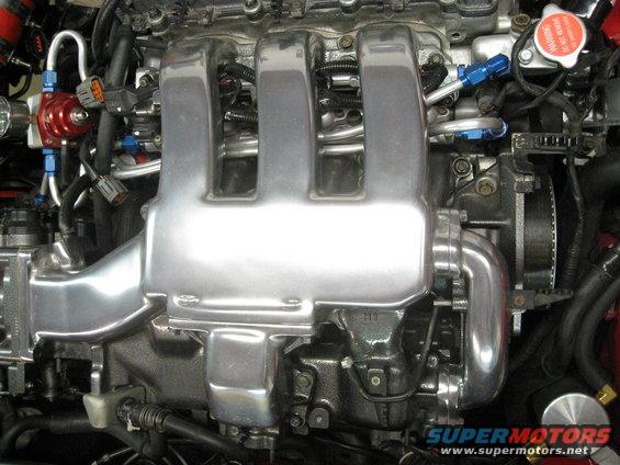 Polished aluminum intake manifold with blue fuel lines and a red fuel pressure regulator