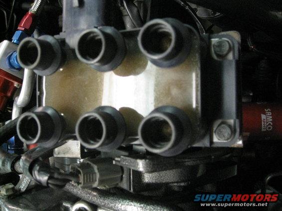 Close-up of a six-terminal ignition coil pack with yellow fluid inside
