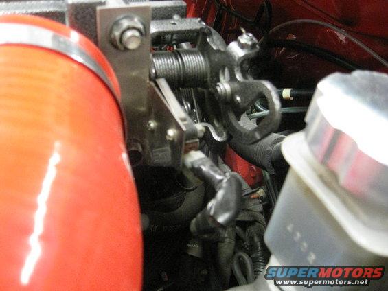 Close-up of a red intake pipe connected to a throttle body assembly with visible springs and linkages