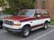 1993 Ford Bronco - This two-tone Ford Bronco is parked in a lot, showing its front three-quarter profile.