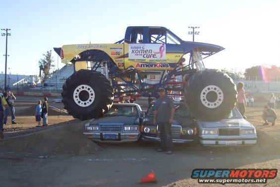 Monster truck with yellow and blue body crushing cars on a dirt track
