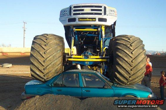 Monster truck front view crushing a teal sedan