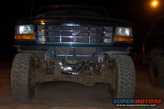 1995 Ford Bronco front end, covered in mud, with another vehicle partially visible to the right