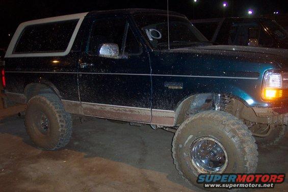 Dark green Ford Bronco, lifted with large tires, covered in mud