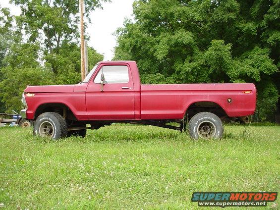 Side view of red 1979 Ford F-150 pickup truck parked in grassy field