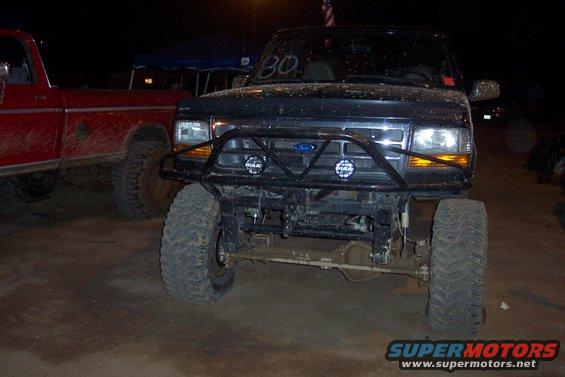 1995 Ford Bronco front end with aftermarket bumper and lights, parked next to a red pickup truck