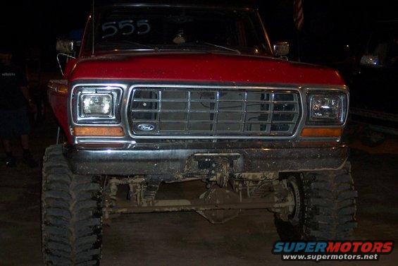 Red Ford F-Series truck with large tires and a chrome grille. '555' is written on the windshield