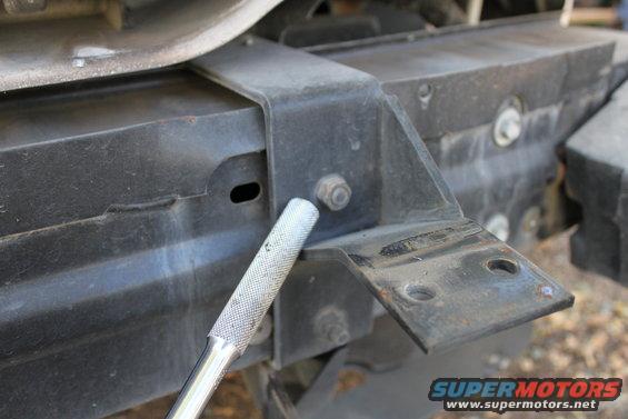 Close-up of a black metal push bar mounting bracket being attached with a socket wrench