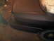 2003 Ford Crown Victoria - Rear quarter panel of a dark sedan, possibly undergoing repair or painting, with a primer finish.