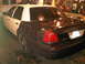 2003 Ford Crown Victoria - This 2003 Ford Crown Victoria police car, seen from the rear, has a white top and black lower body, with license plate EEJ 762 visible.