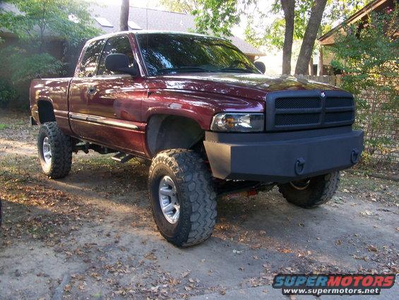 Red 2001 Dodge 1500 pickup truck with aftermarket bumper and large tires, parked outdoors